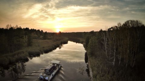 Ein freecamper mit Wohnmobil fährt auf  der Havel dem Sonnenaufgang entgegen.